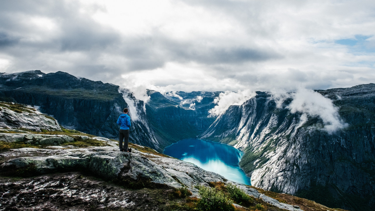 Foto: Mann står og ser ut over Tyssedal fra et fjell og ned mot et vann. 
