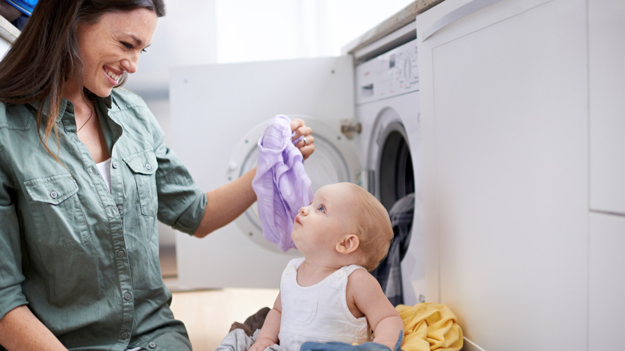 Shot of a mother and her baby girl playing while doing laundry