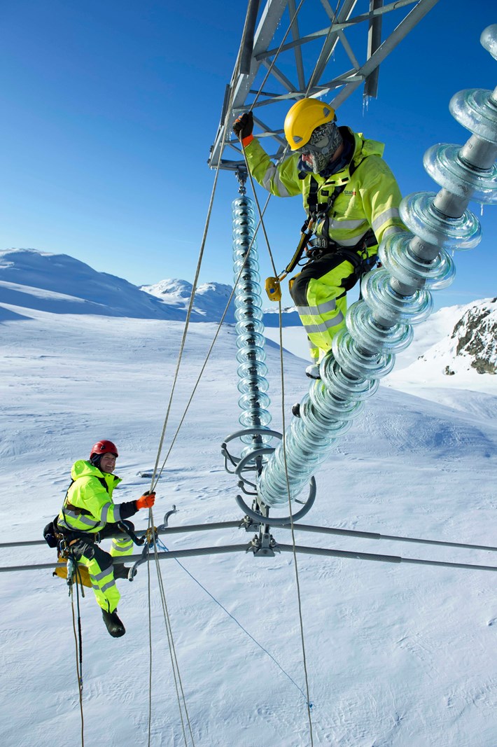 To energimontører arbeider på strømnettet i snøen. Foto